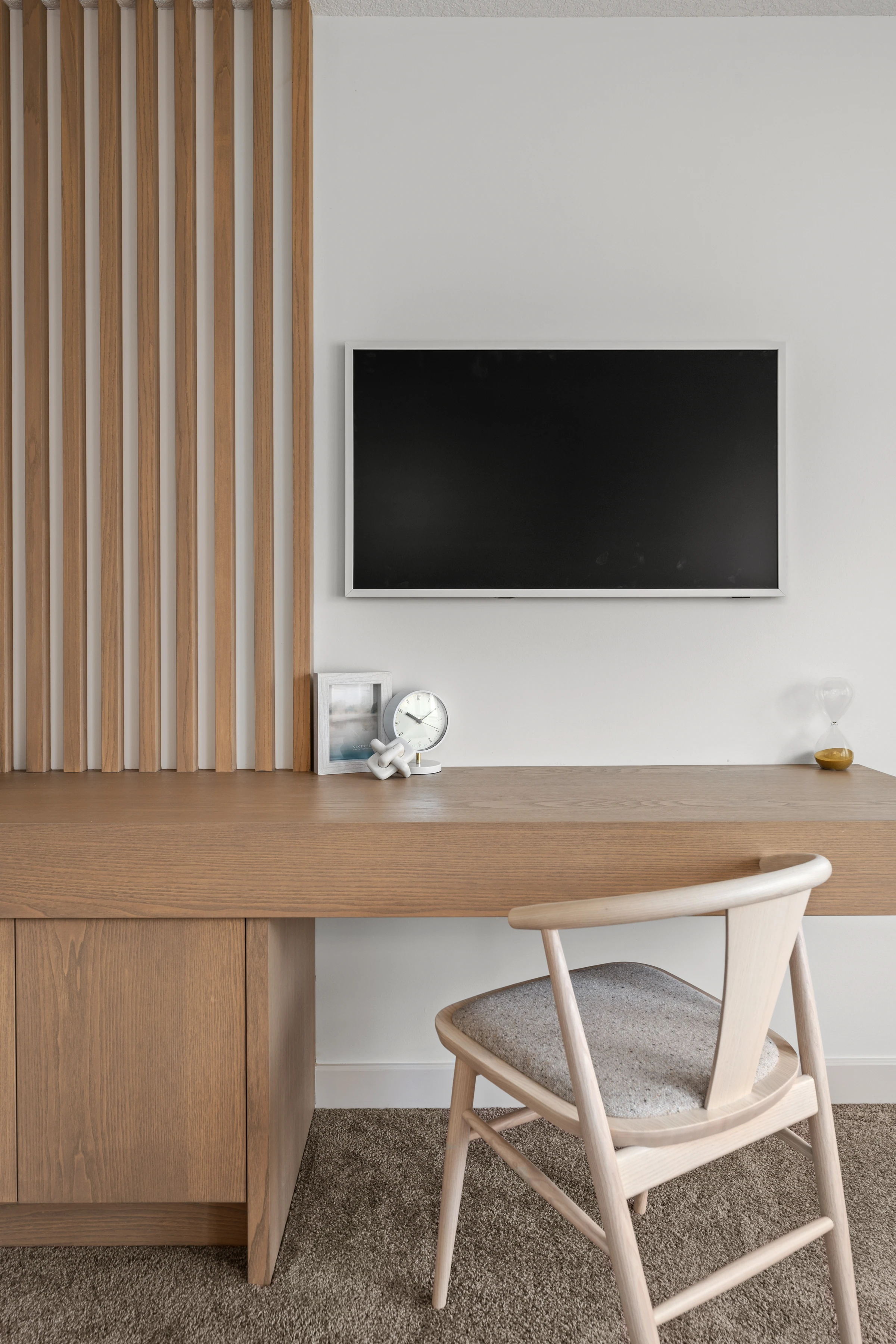 Wood slat feature wall with a wall-mounted TV above a built-in desk