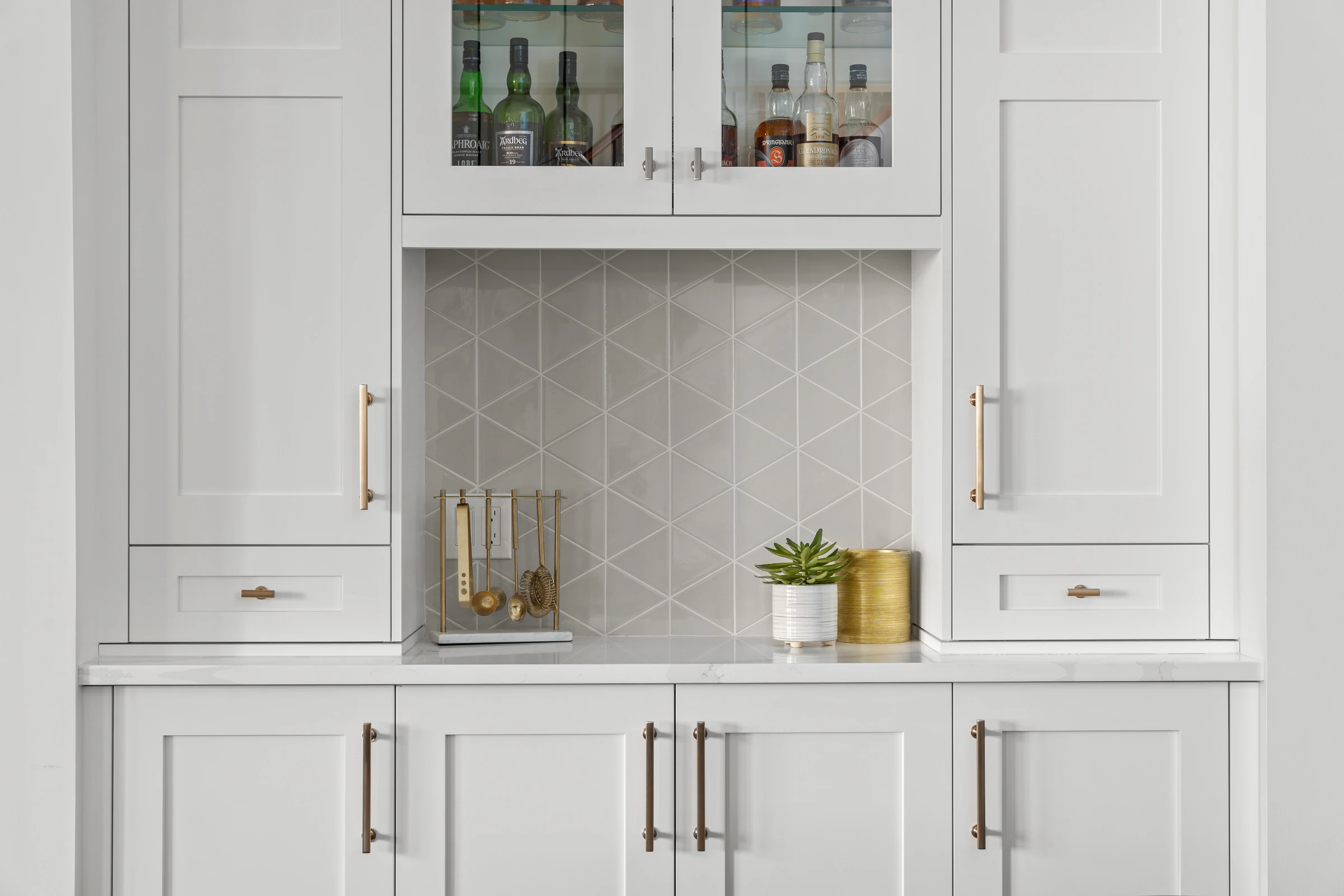 Built-in bar cabinet detail with glass-front doors and patterned tile backsplash