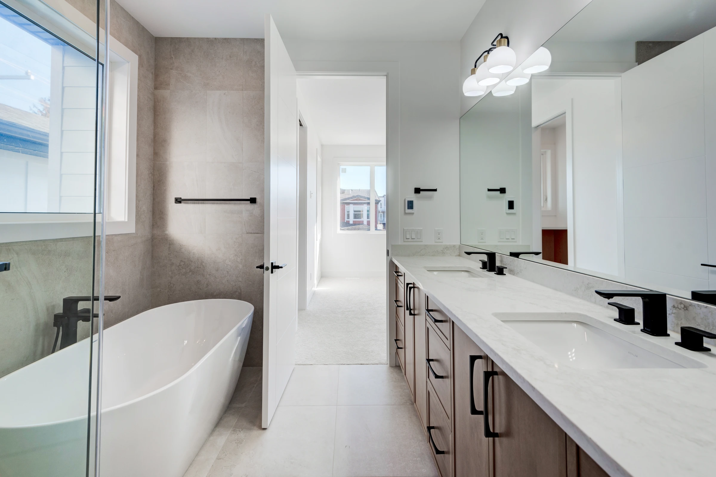 Ensuite bathroom with a freestanding tub, double vanity, and a view down the hallway