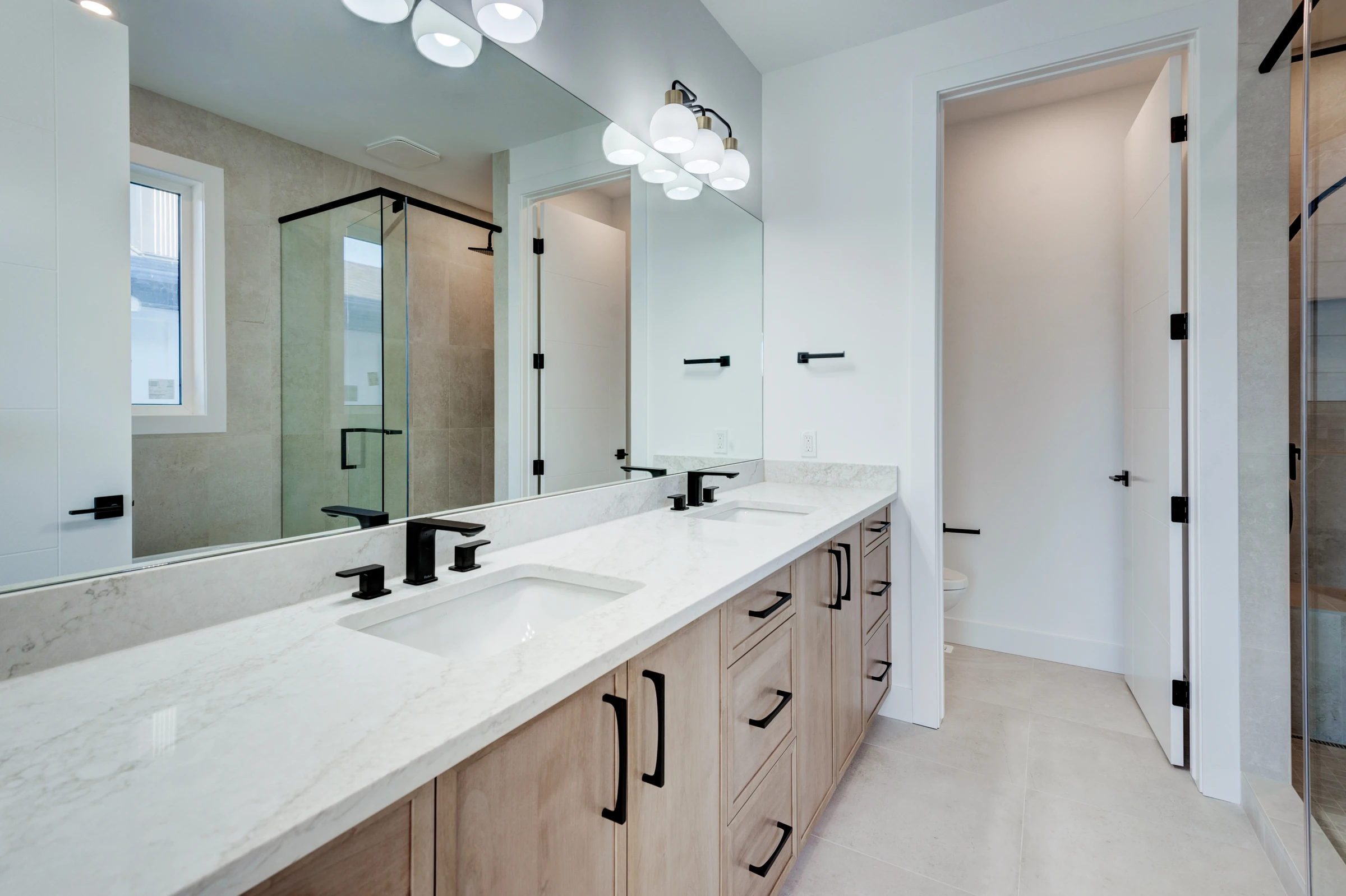 Double vanity and walk-in shower in a primary ensuite with wood cabinetry