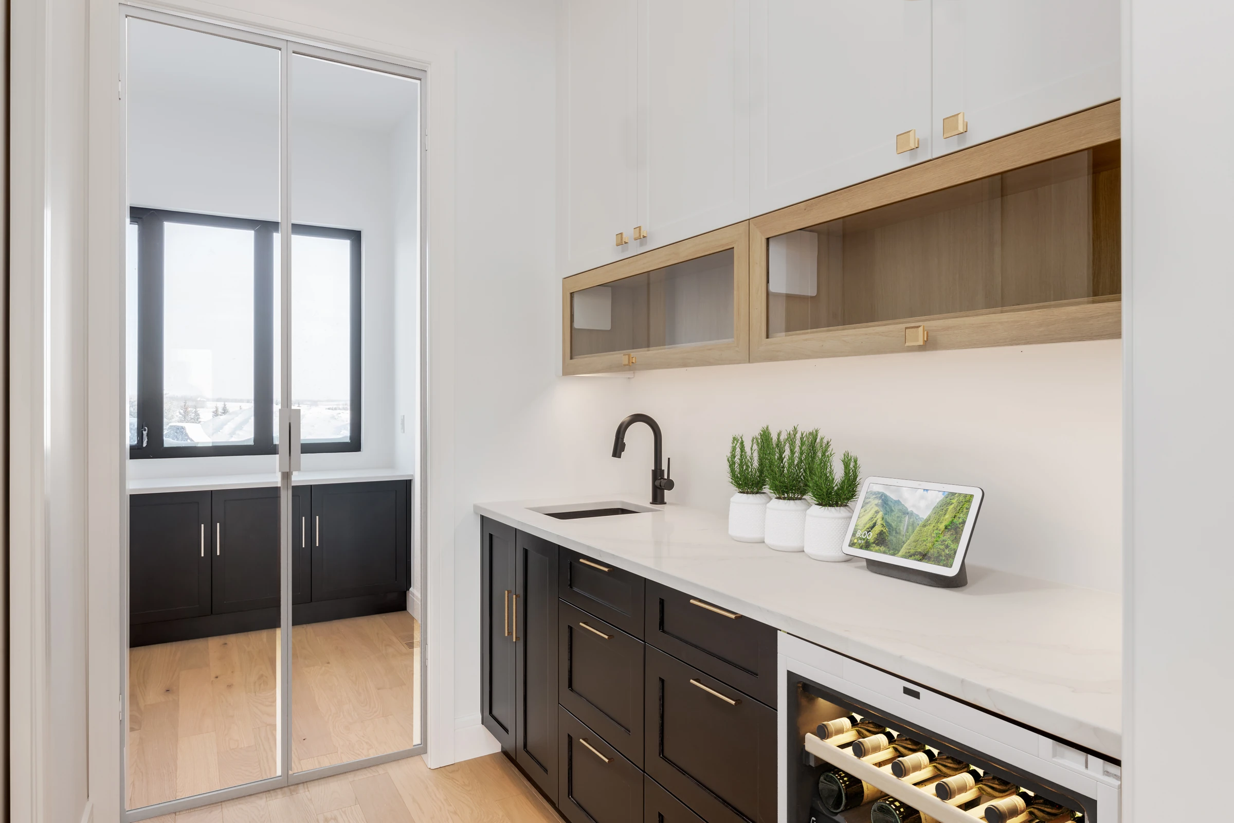 Butler's pantry with black cabinetry, mirrored doors, and a small prep sink