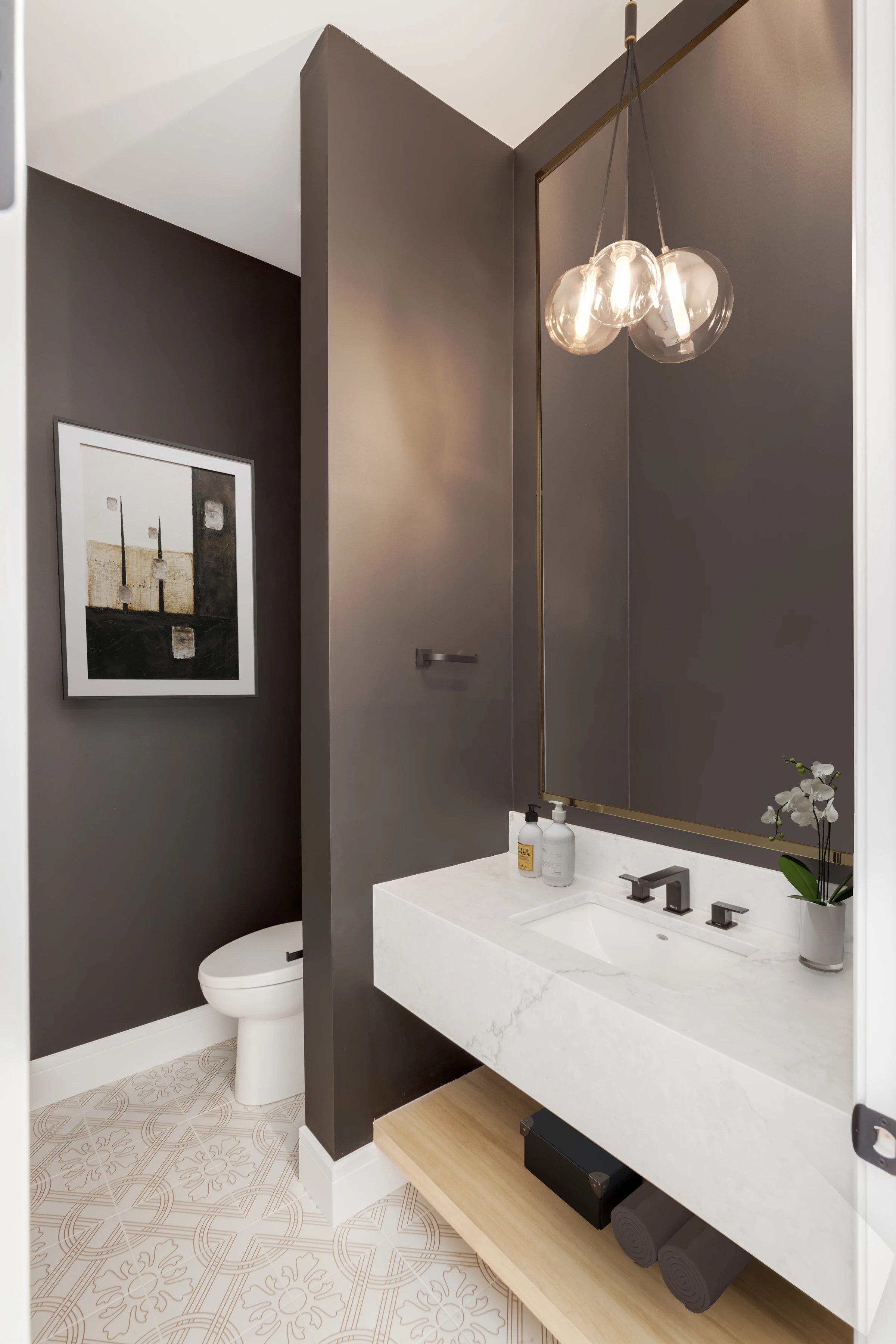 Moody powder room with dark walls, a floating marble vanity, and a brass pendant