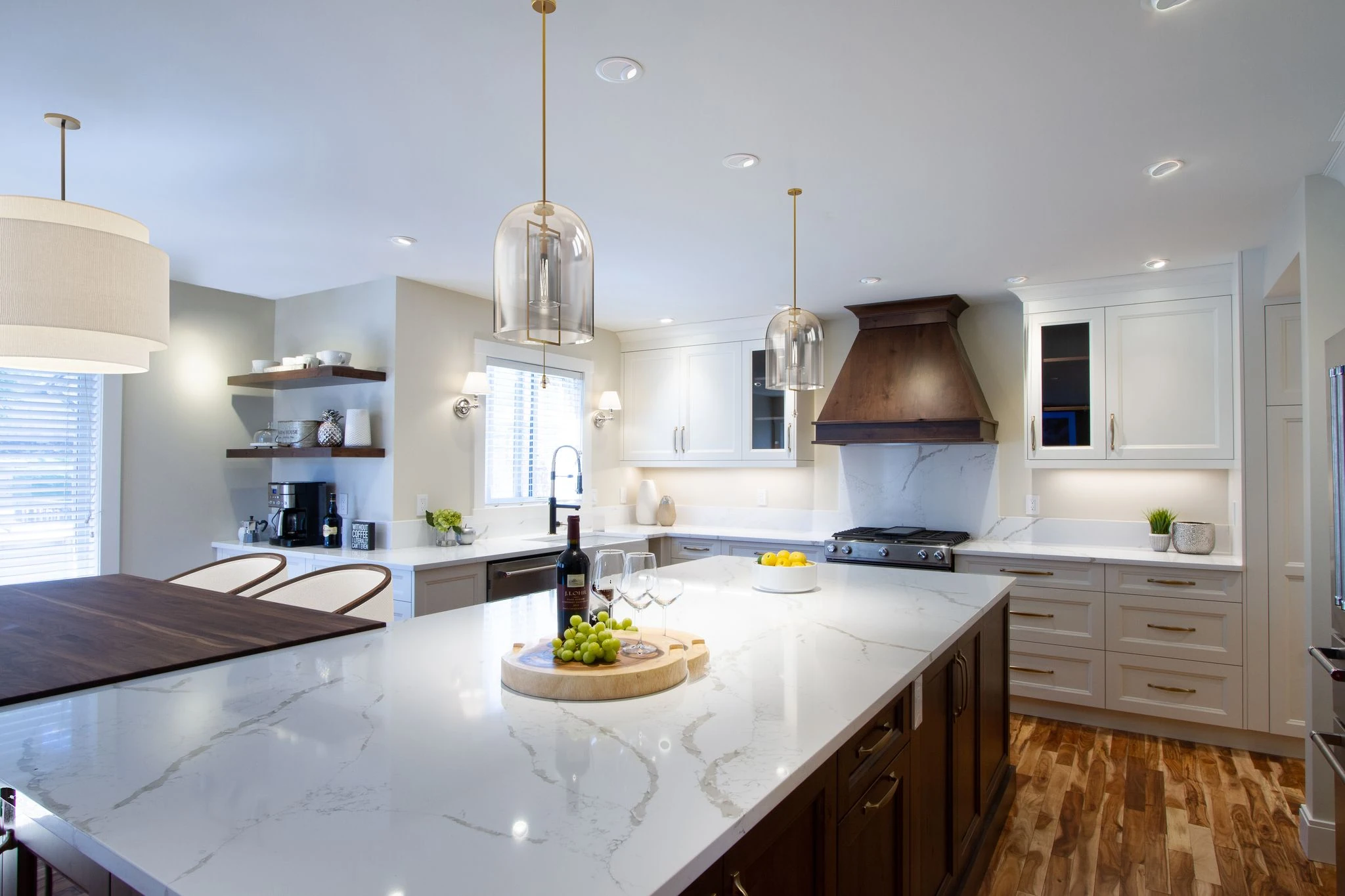Kitchen island with a drum pendant light, glass pendants, and a marble waterfall countertop