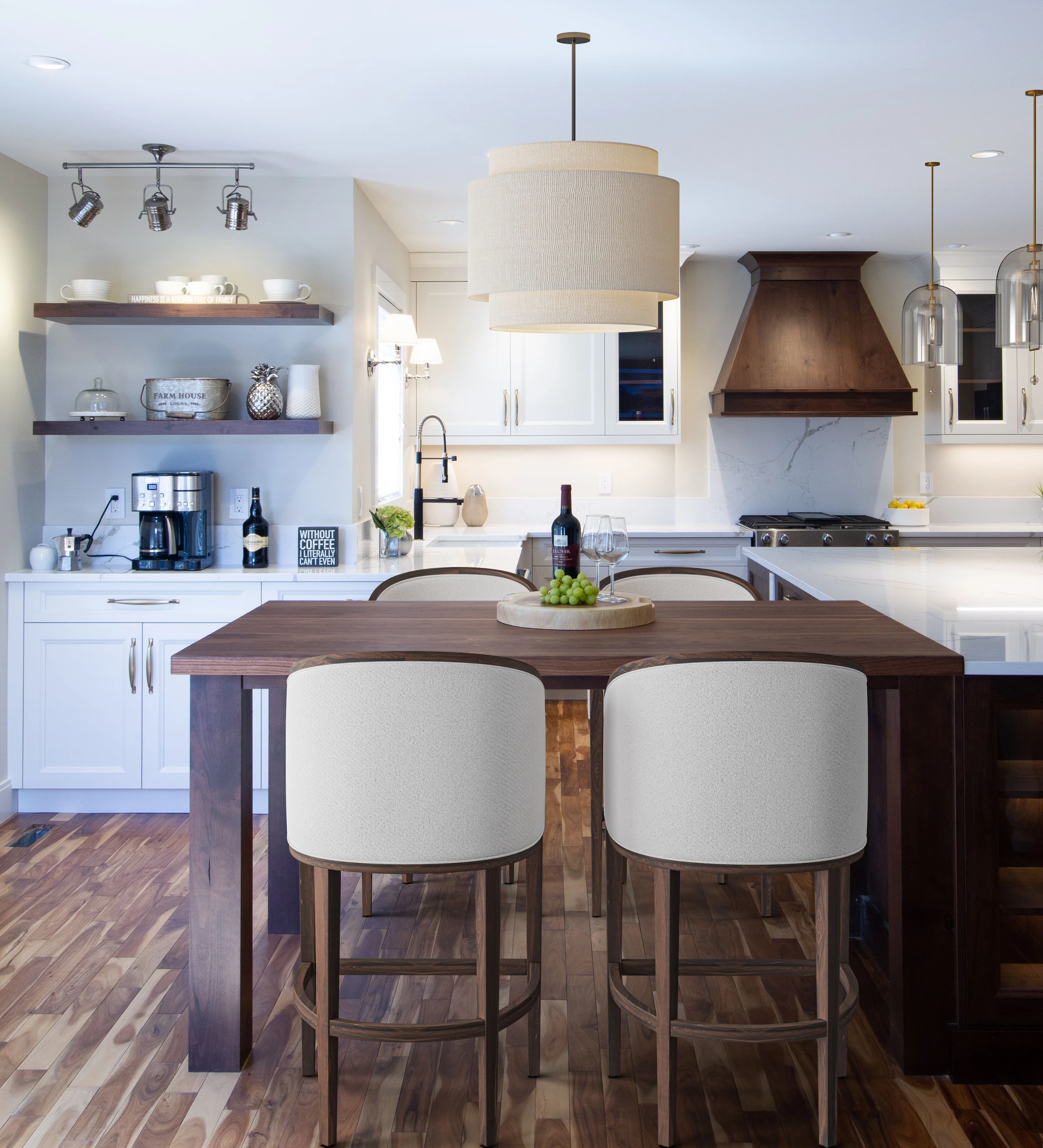 Dining table with upholstered chairs in front of a kitchen island and wood range hood