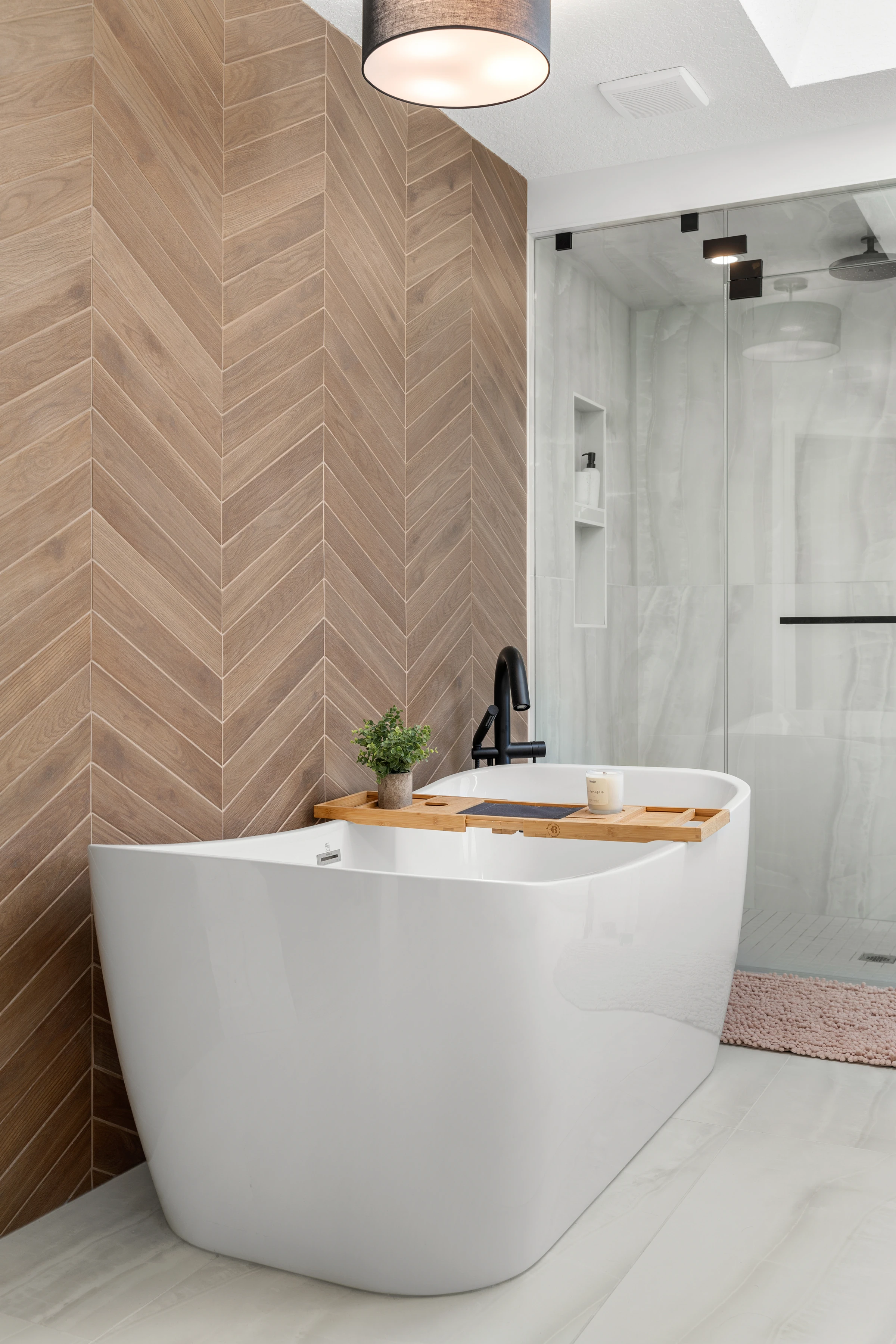 Freestanding tub against a chevron wood accent wall with a walk-in shower beyond