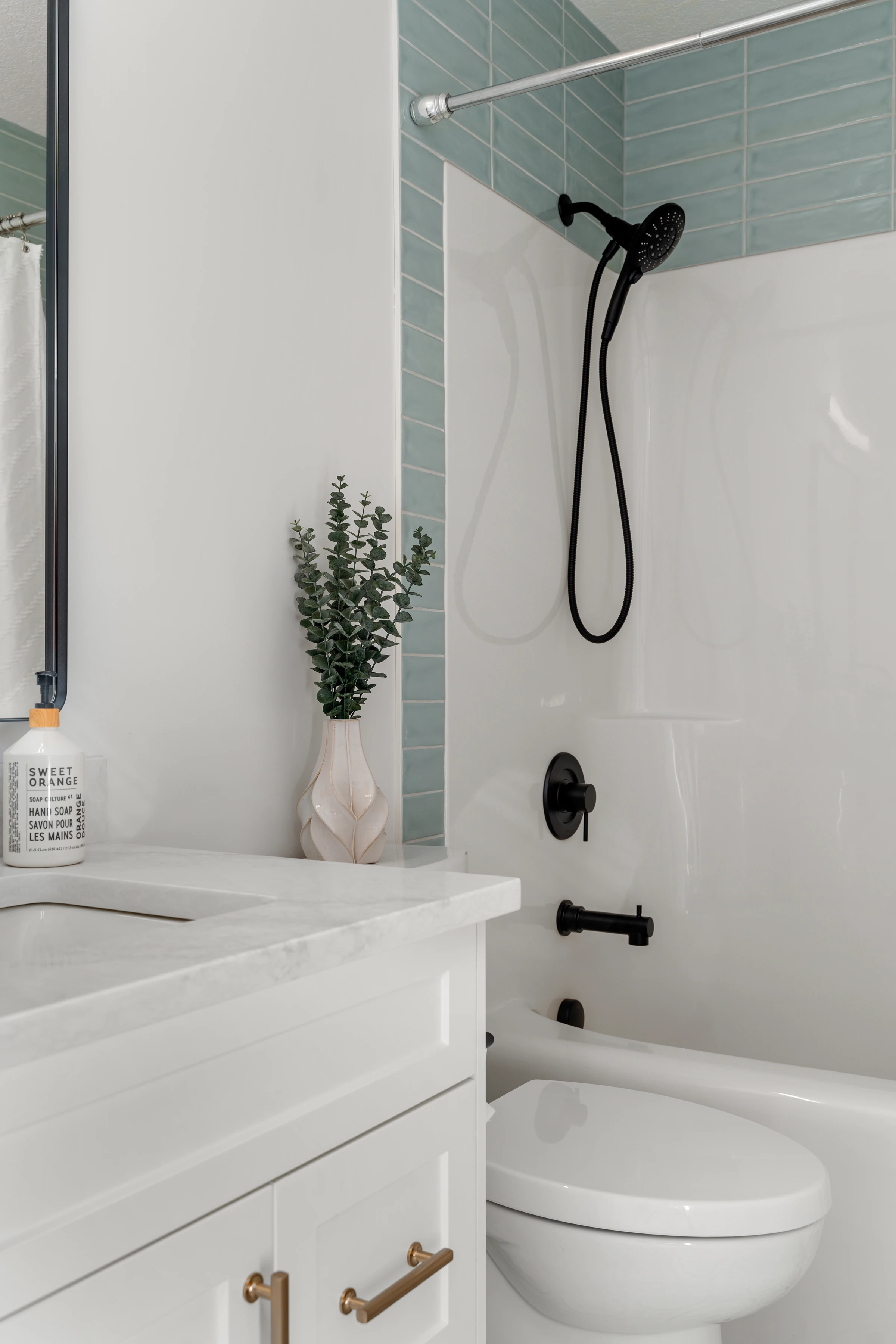 Secondary bathroom with a green subway-tile tub surround and matte black fixtures