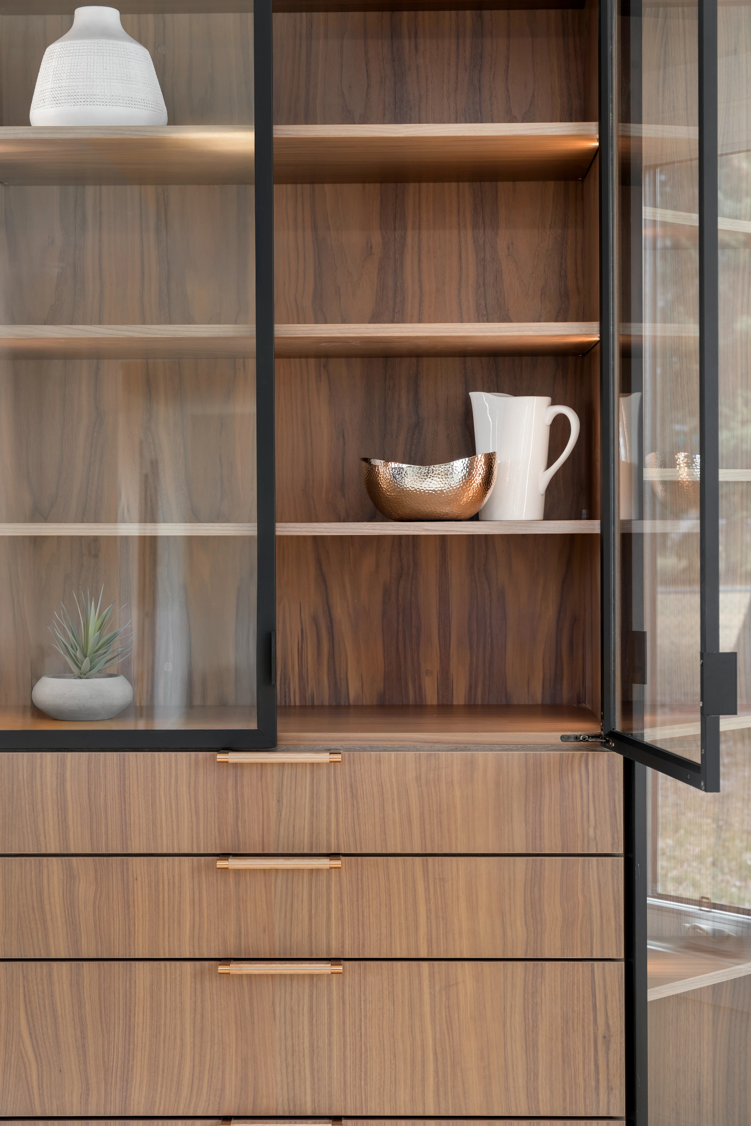 Walnut china cabinet detail with brass hardware and curated dishware