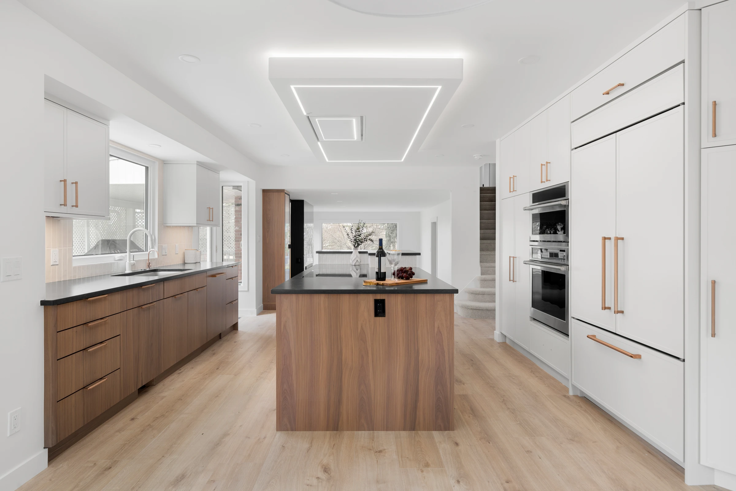 Kitchen with a sculptural ceiling light, black countertops, and walnut and white cabinetry