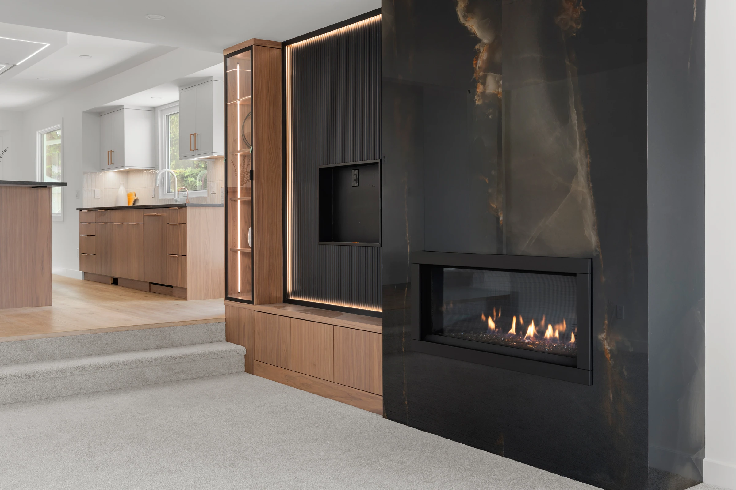 Black stone fireplace wall with a built-in wood cabinet beside the stairs