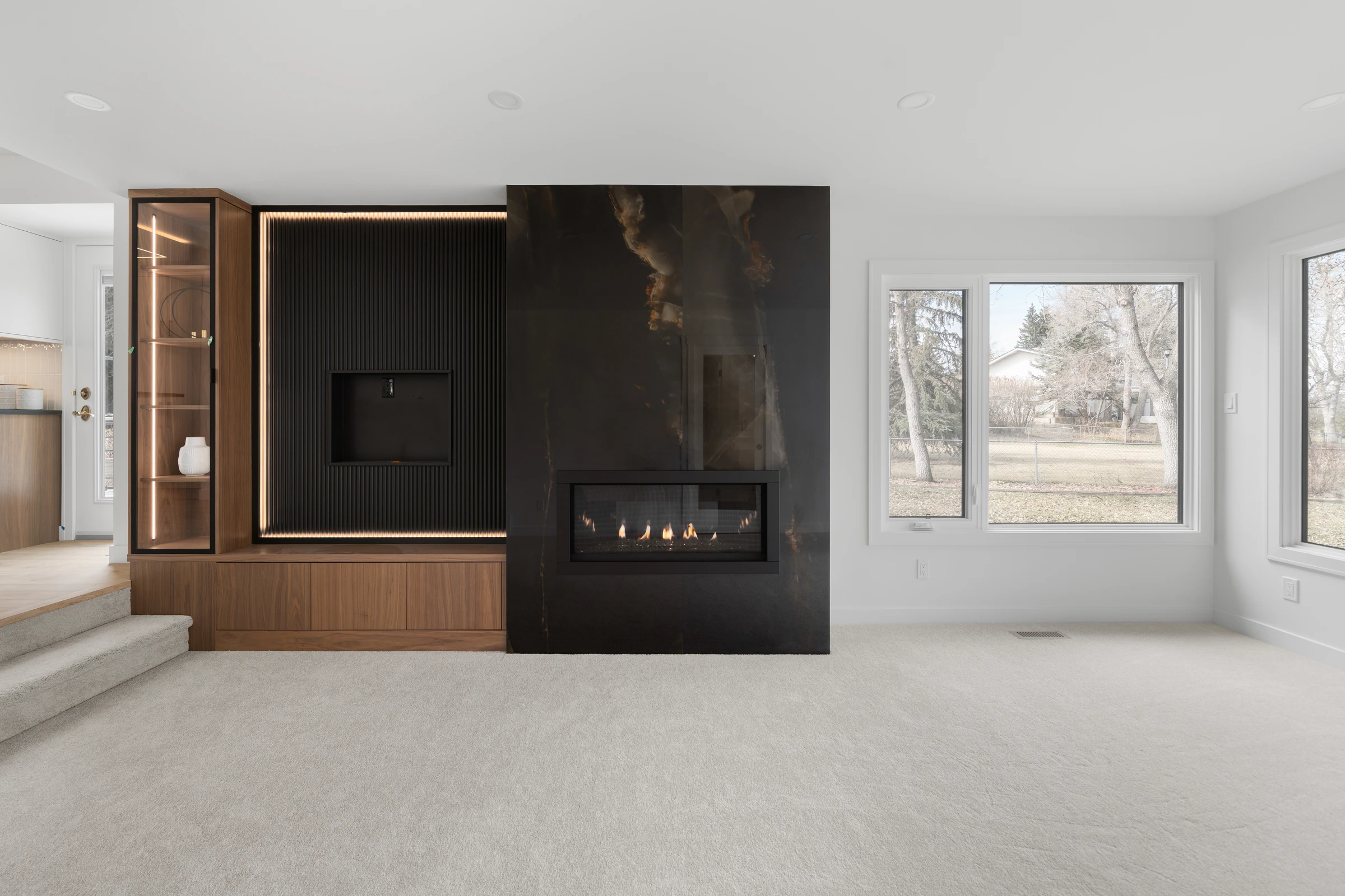 Living room fireplace wall with a glass display cabinet and media niche