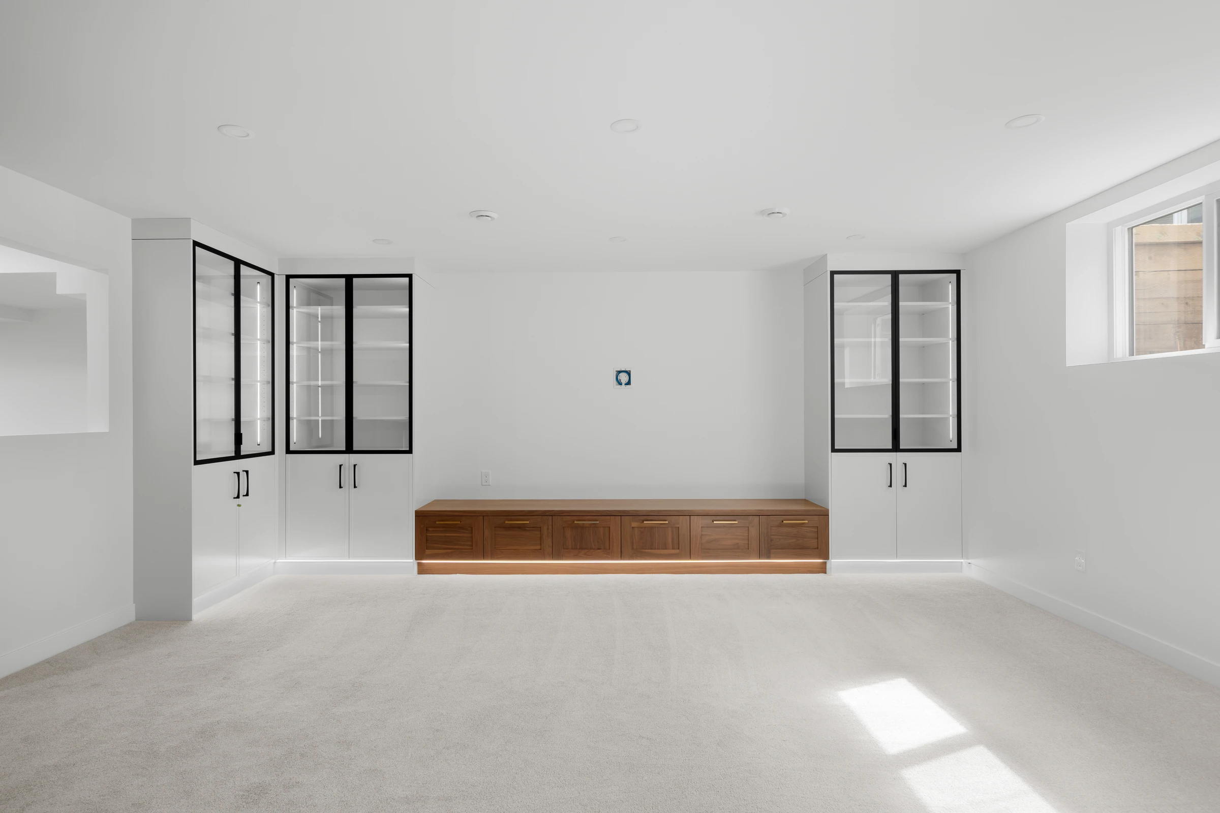 Basement rec room with matching glass-front display cabinets and a walnut media bench
