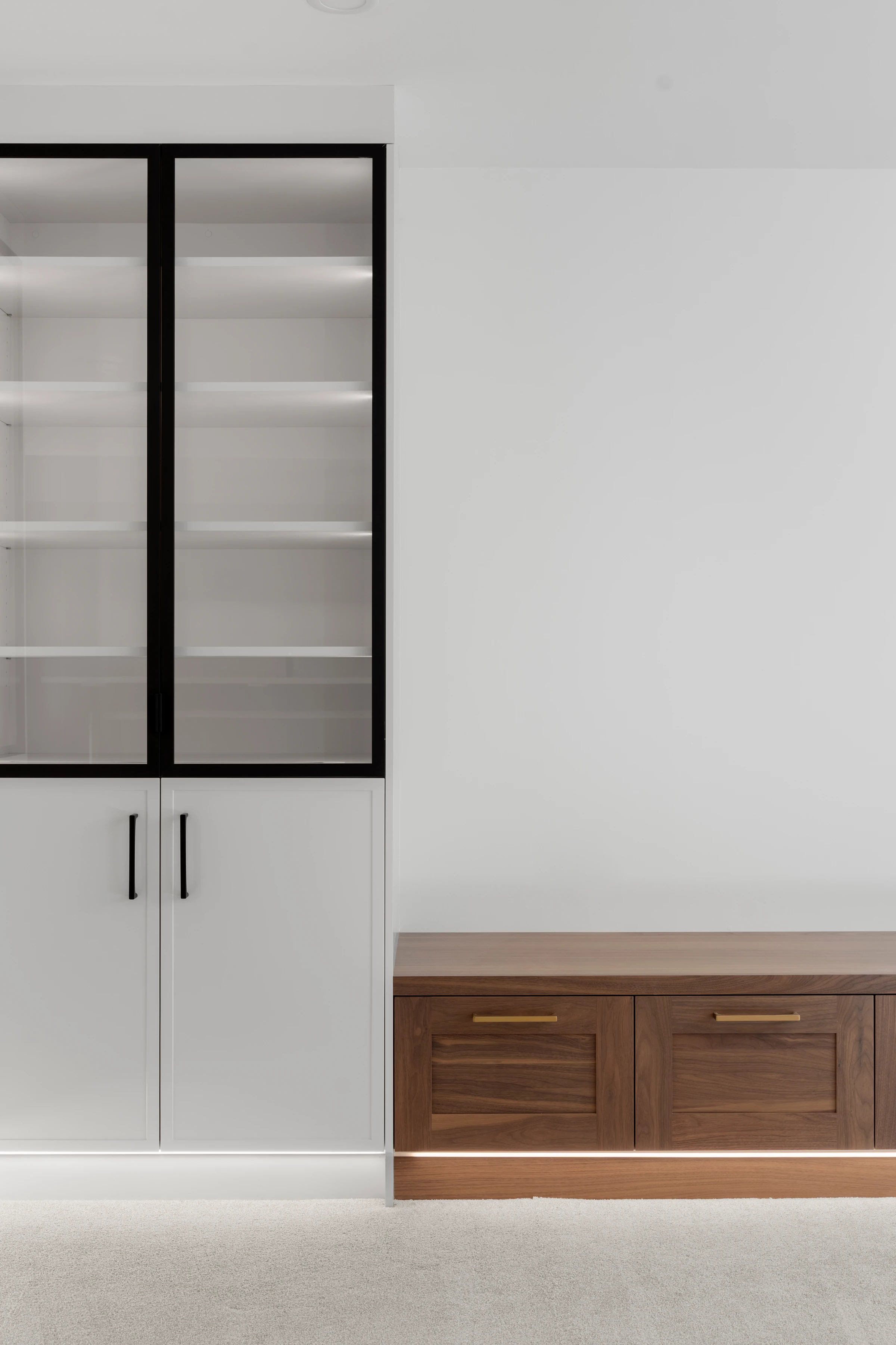 Detail of a glass-front display cabinet and walnut media bench