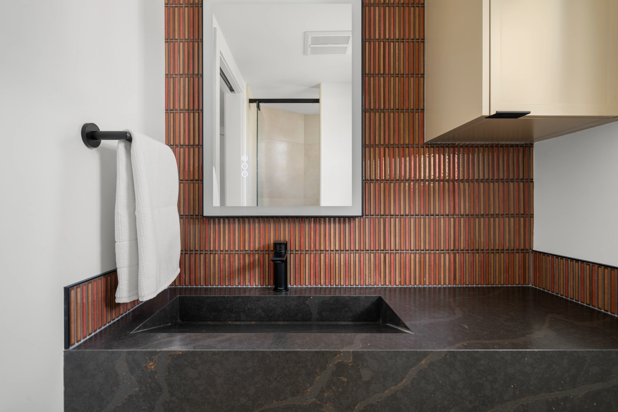 Powder room with terracotta fluted tile and a sculptural black stone vanity