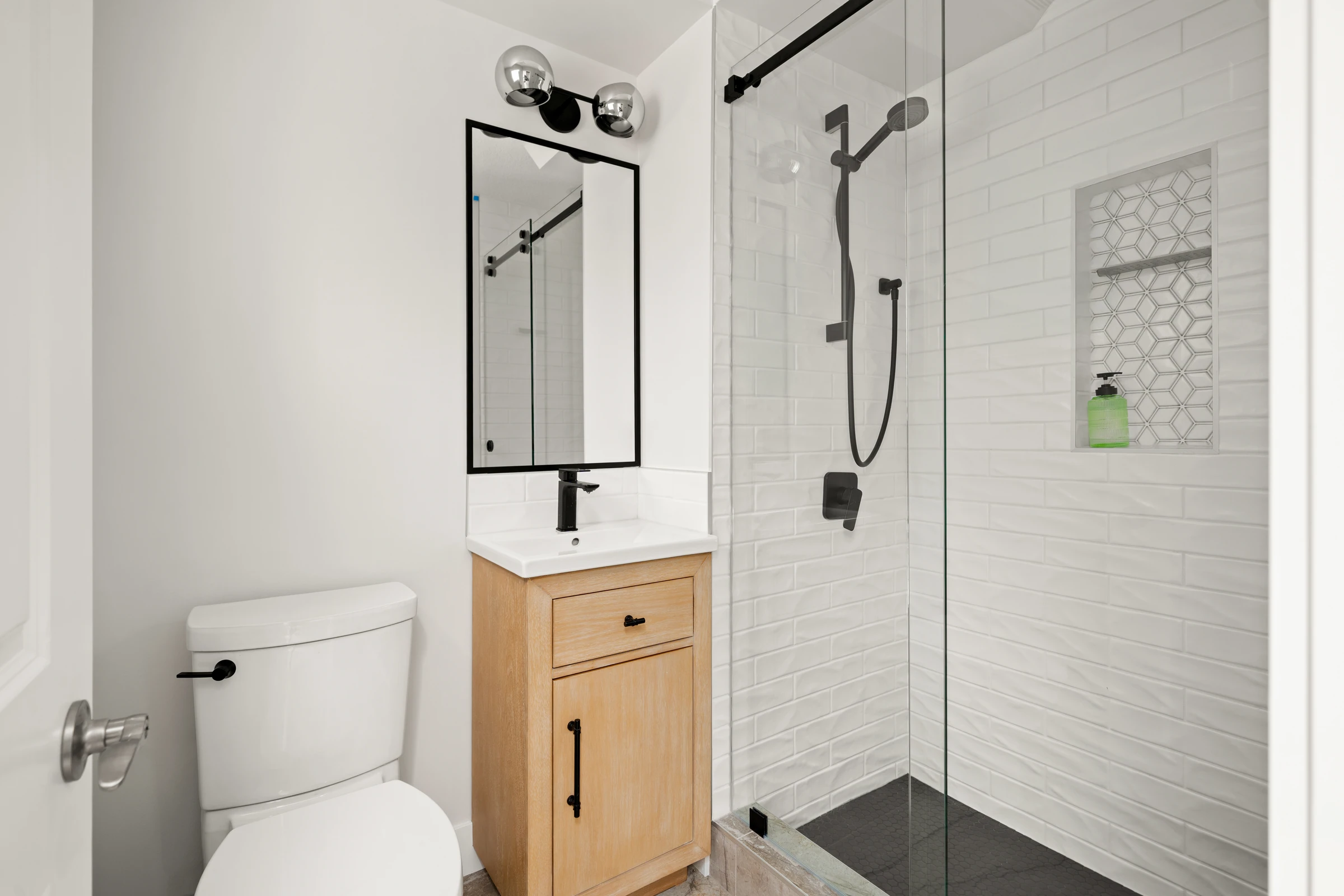 White subway-tile bathroom with matte black fixtures and a walk-in glass shower