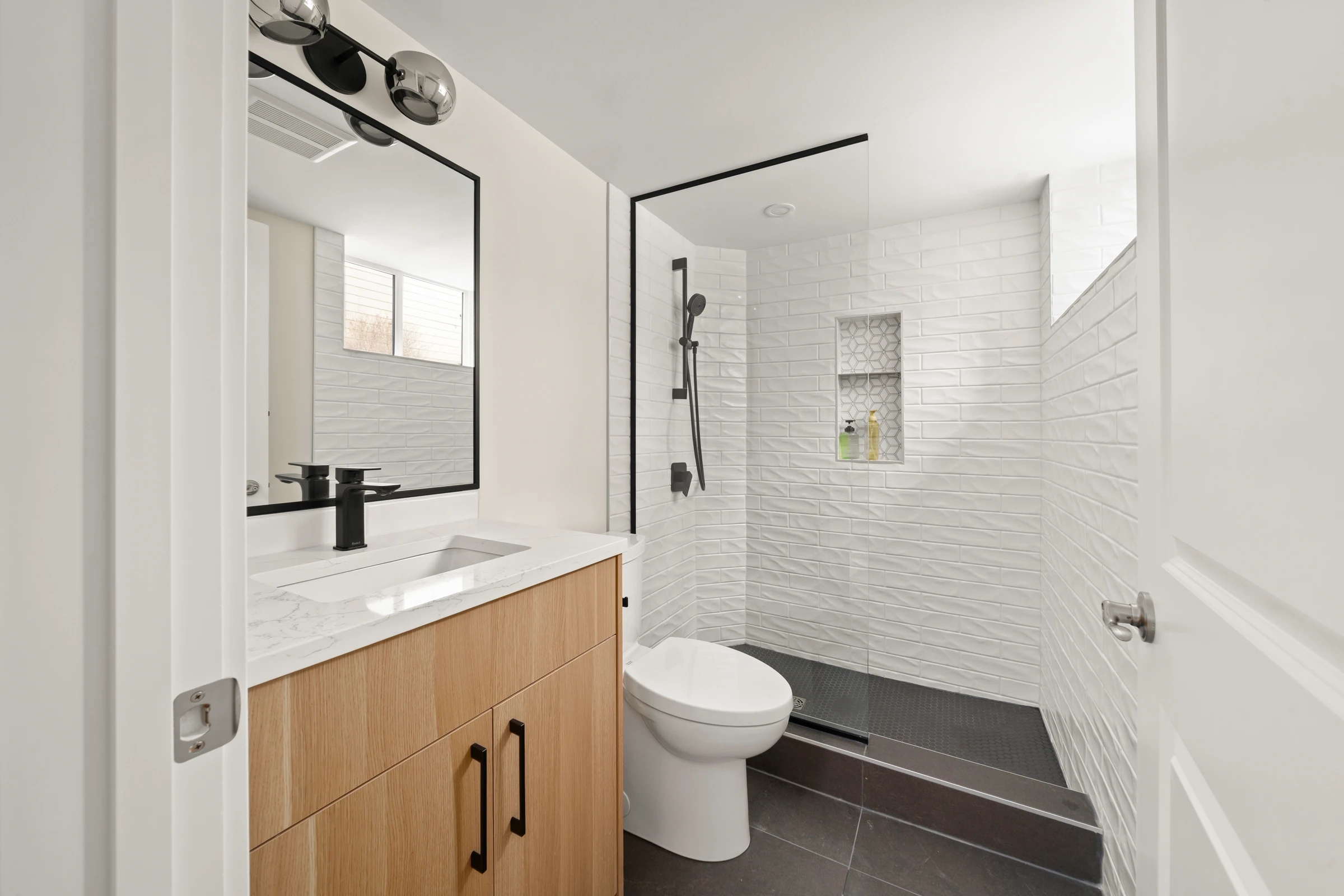 Bathroom vanity and walk-in shower with black hardware and white tile