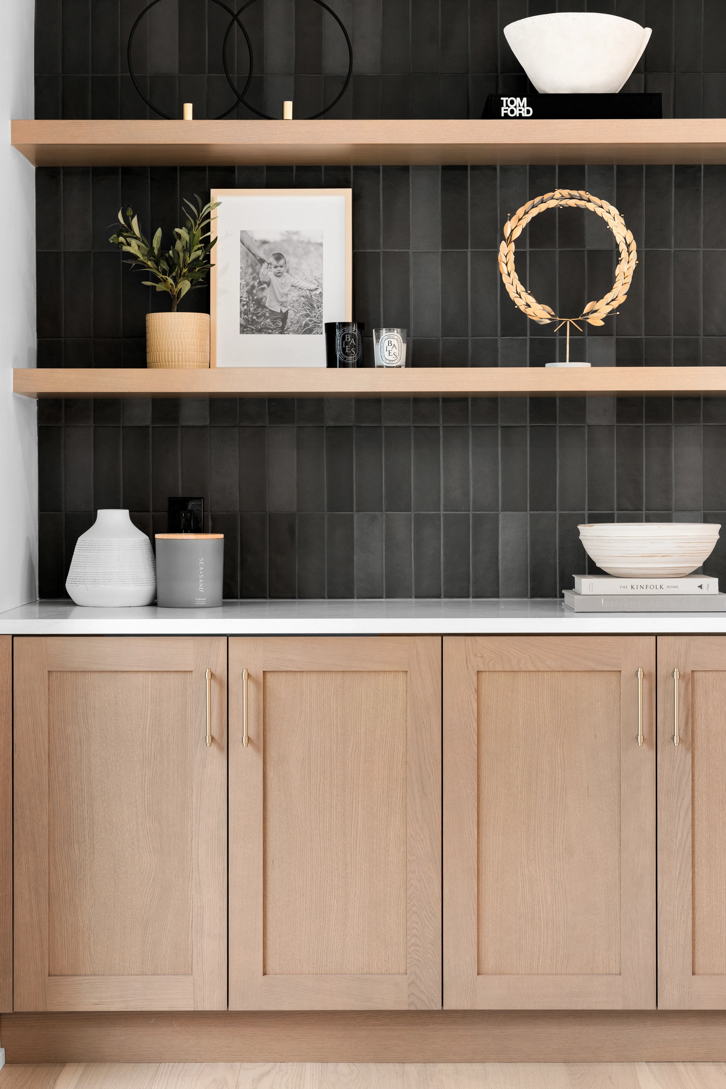 Styled open shelving detail with dark tile backsplash and wood cabinetry