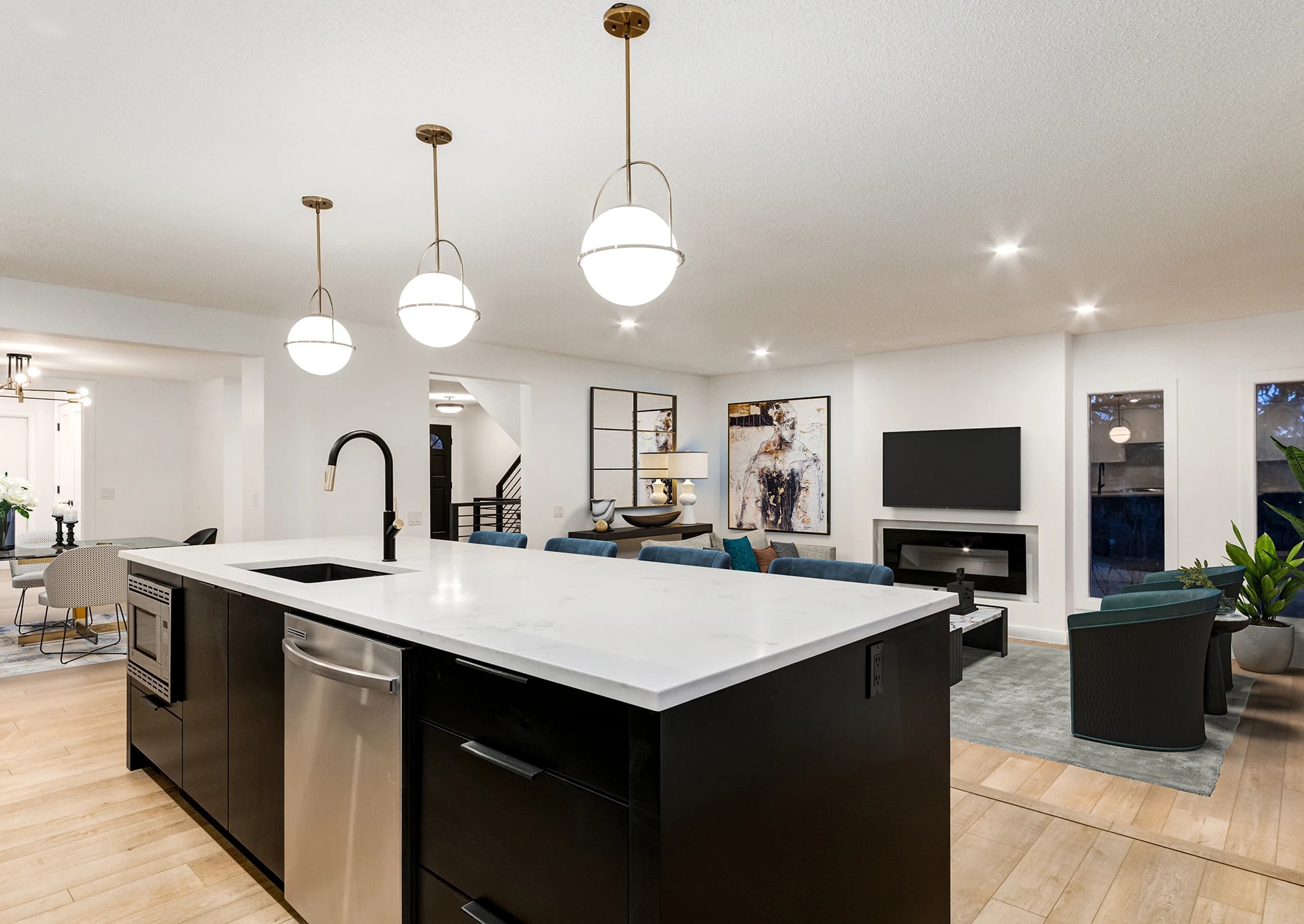 Black kitchen island with globe pendant lighting opening to the living room