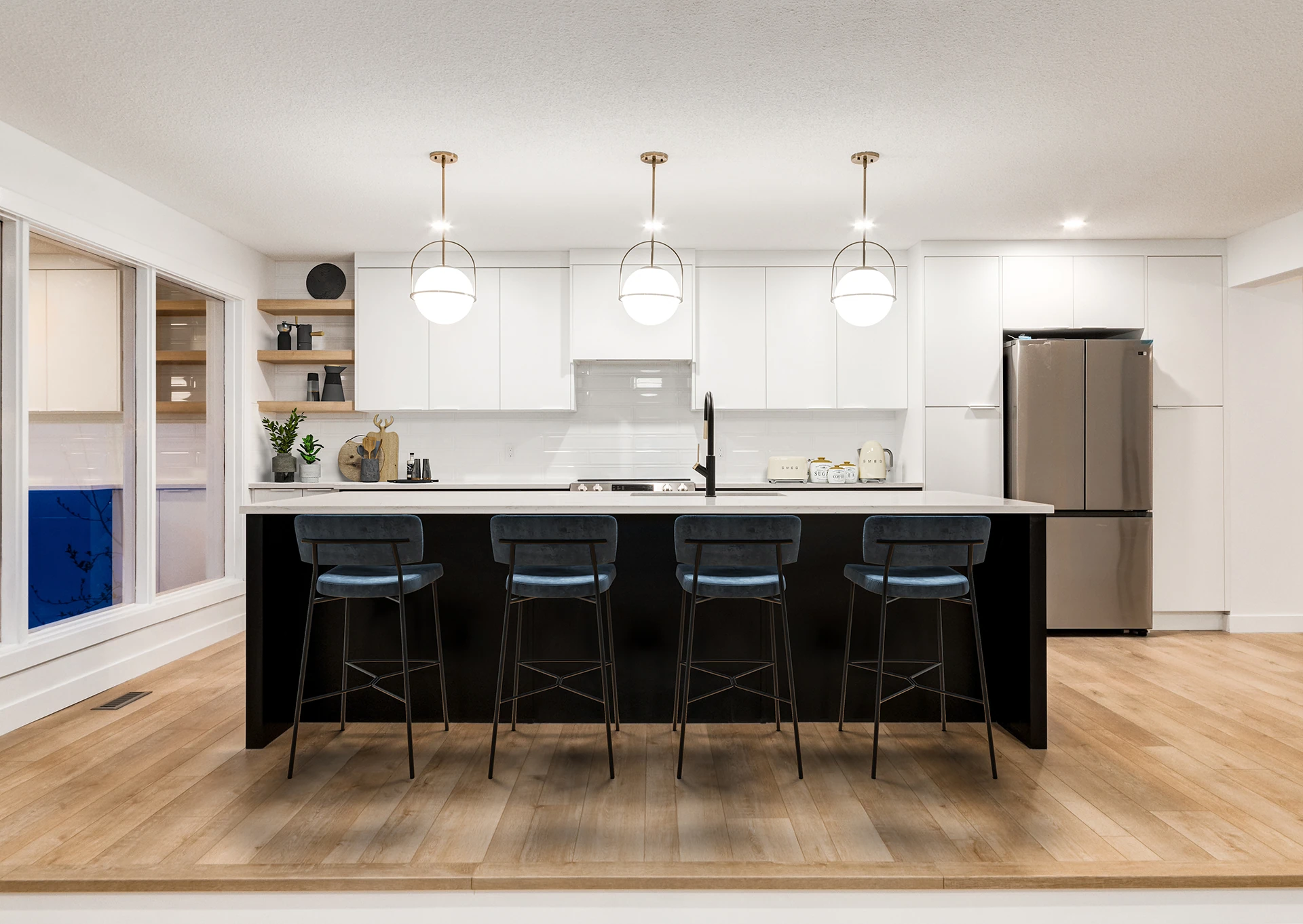 White kitchen with a black island, globe pendants, and blue counter stools