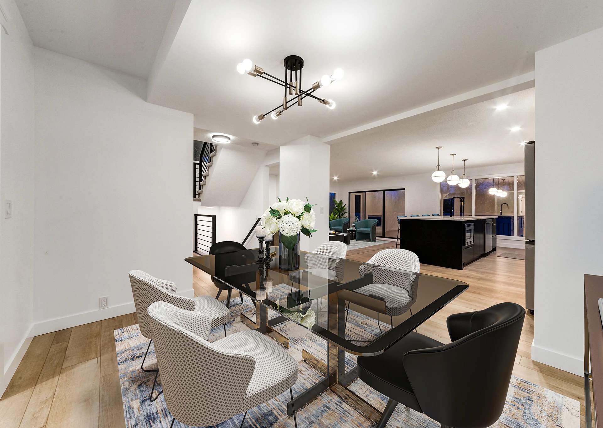 Dining area beneath a sputnik chandelier with a staircase and kitchen in view