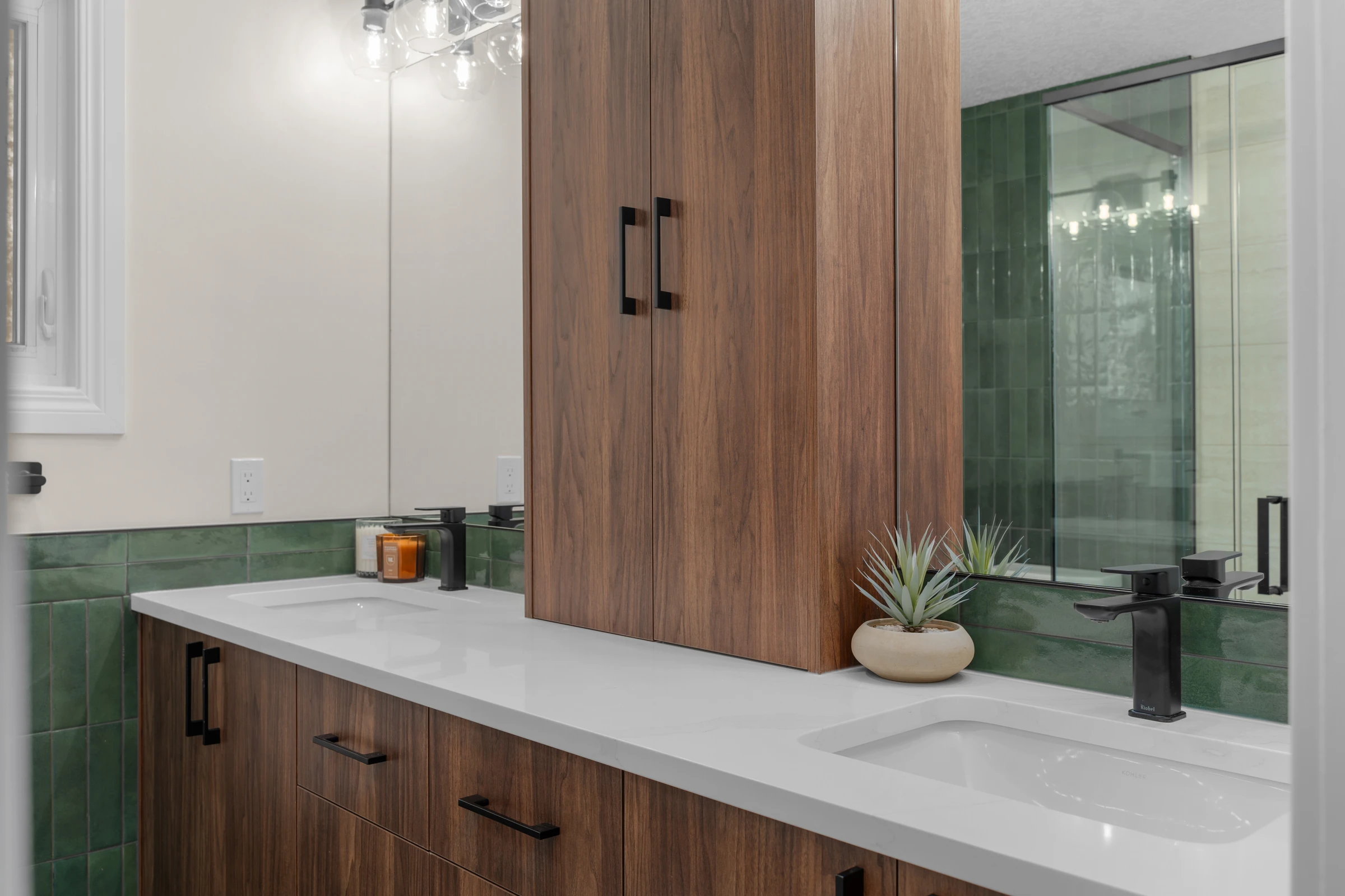 Walnut double vanity with green tile backsplash and a matching linen tower