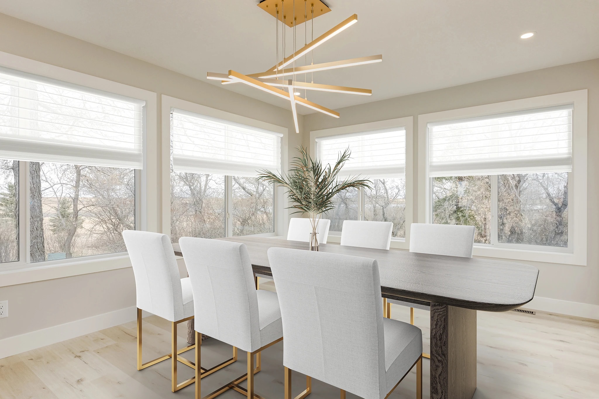 Dining room with a sculptural gold chandelier and a wall of windows overlooking trees