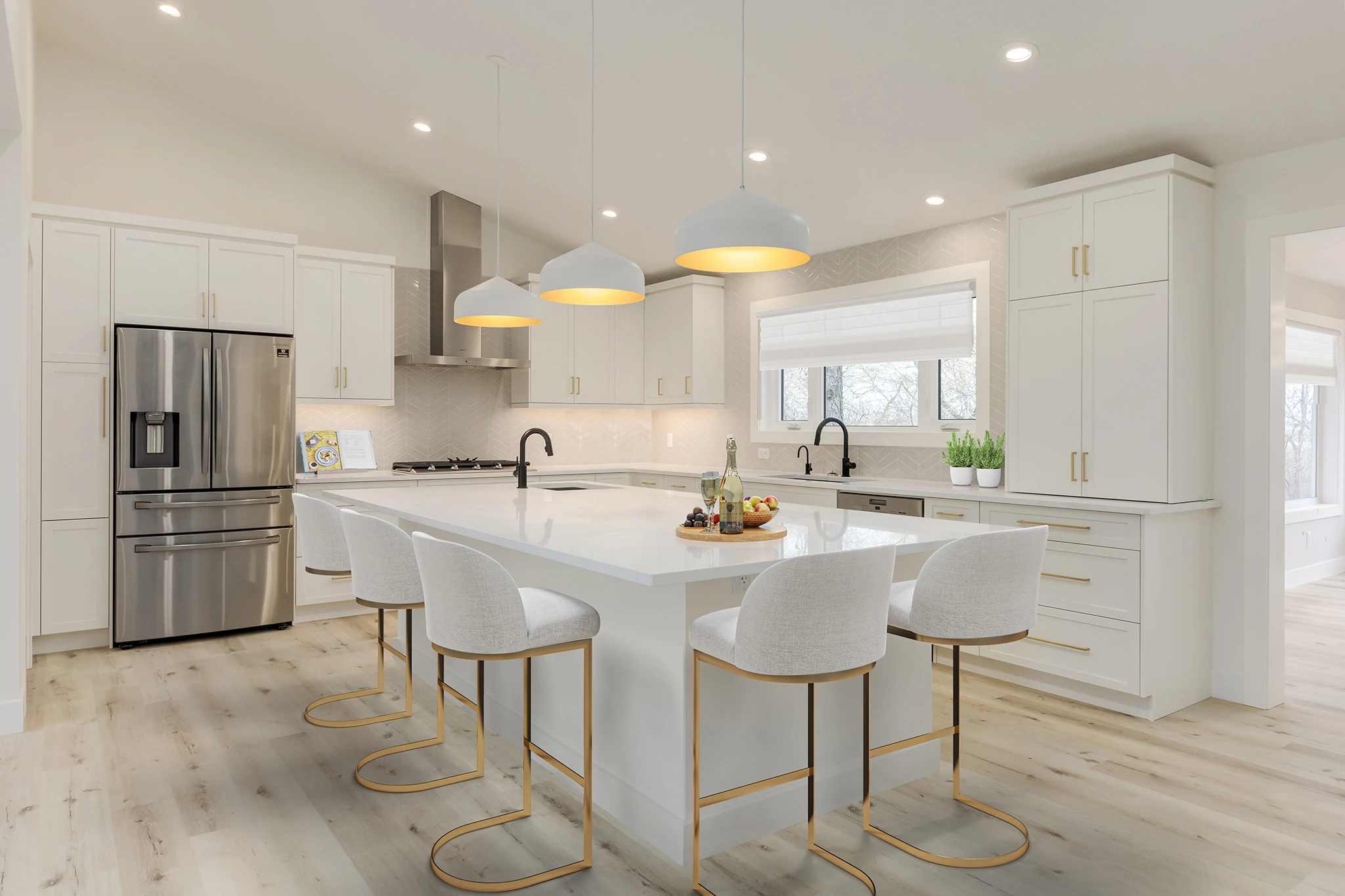 All-white kitchen with a large island, gold pendant lighting, and barstool seating