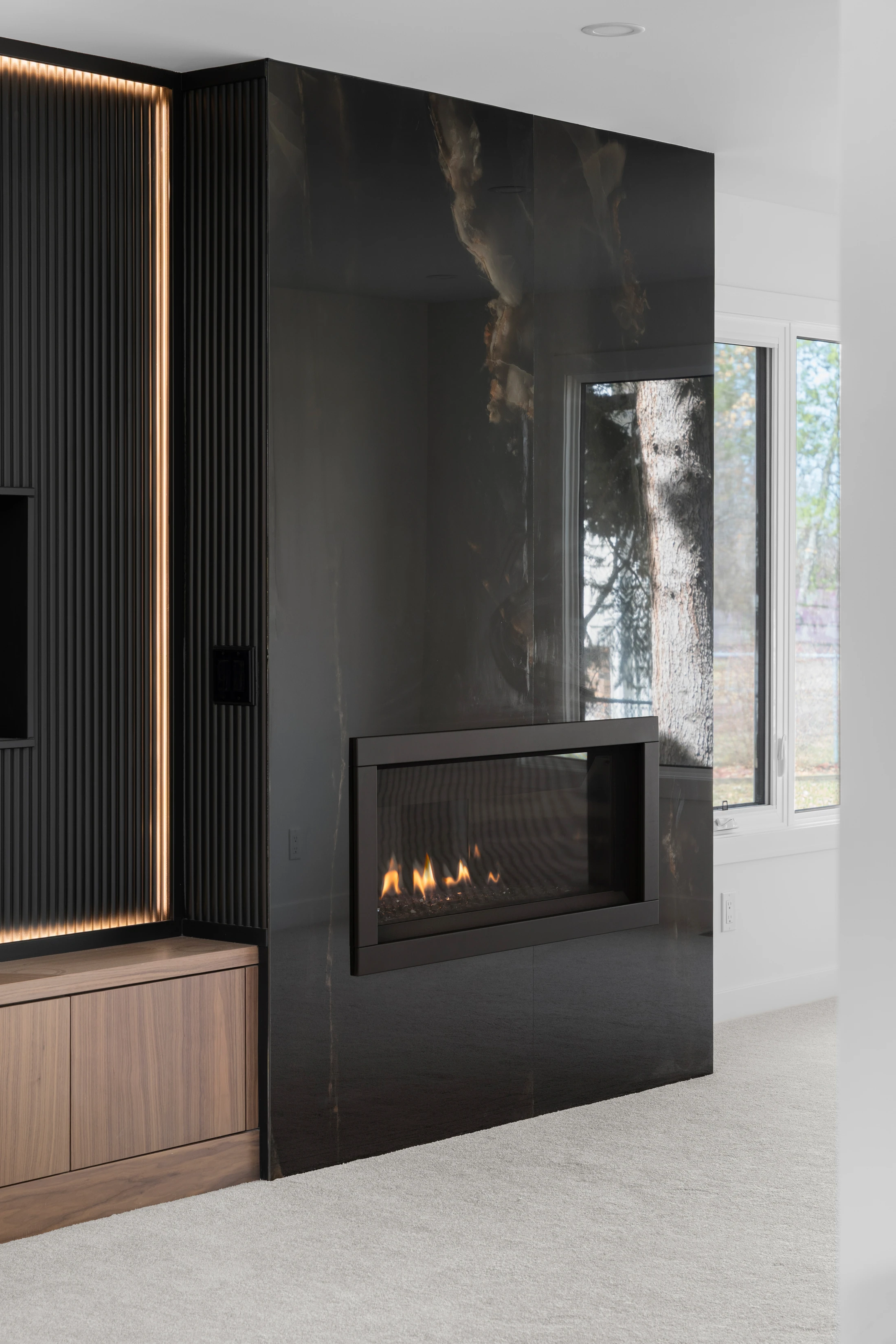 Detail of a black stone fireplace with a wood slat accent wall