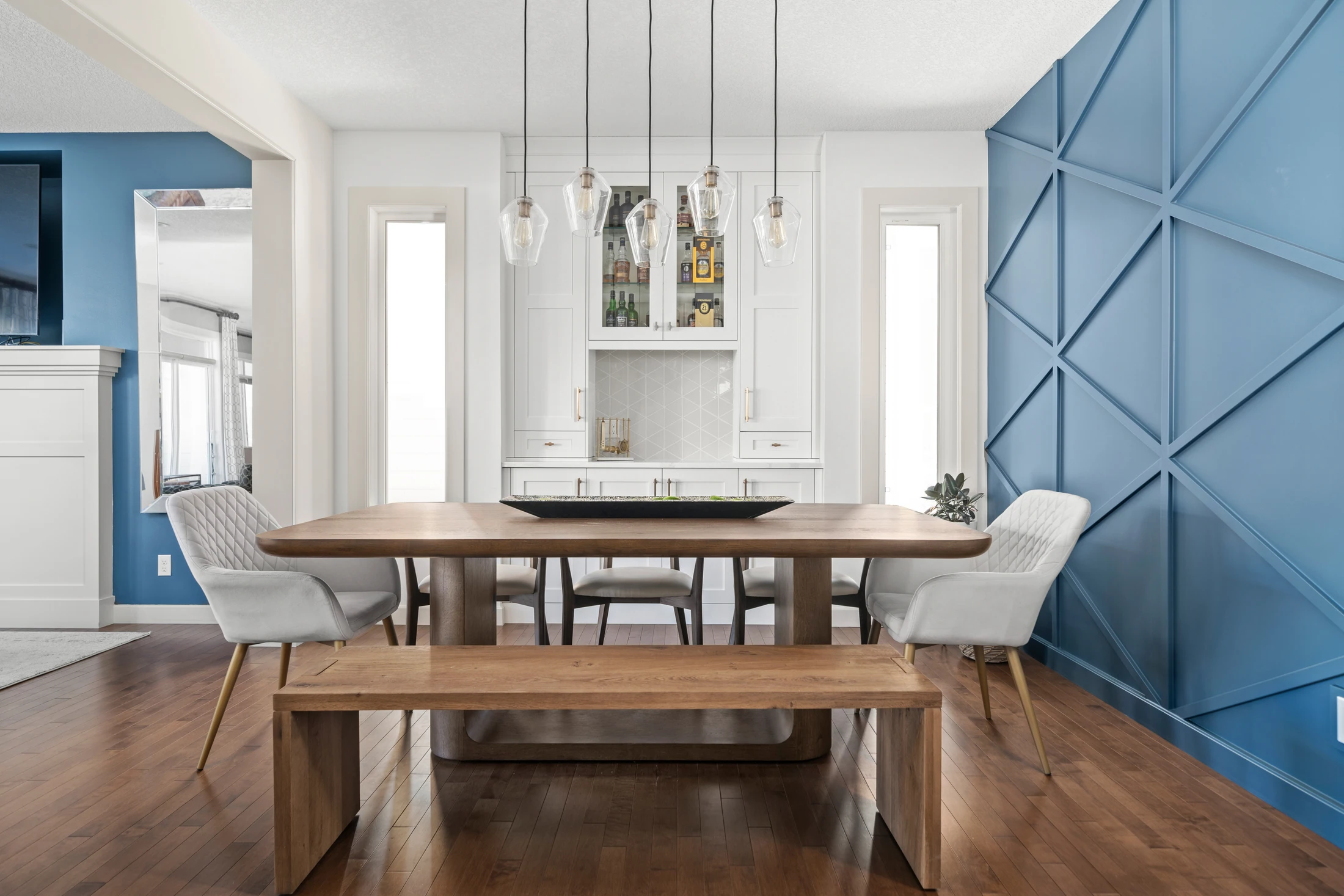 Dining room with a bold blue paneled accent wall and a cluster of glass pendant lights