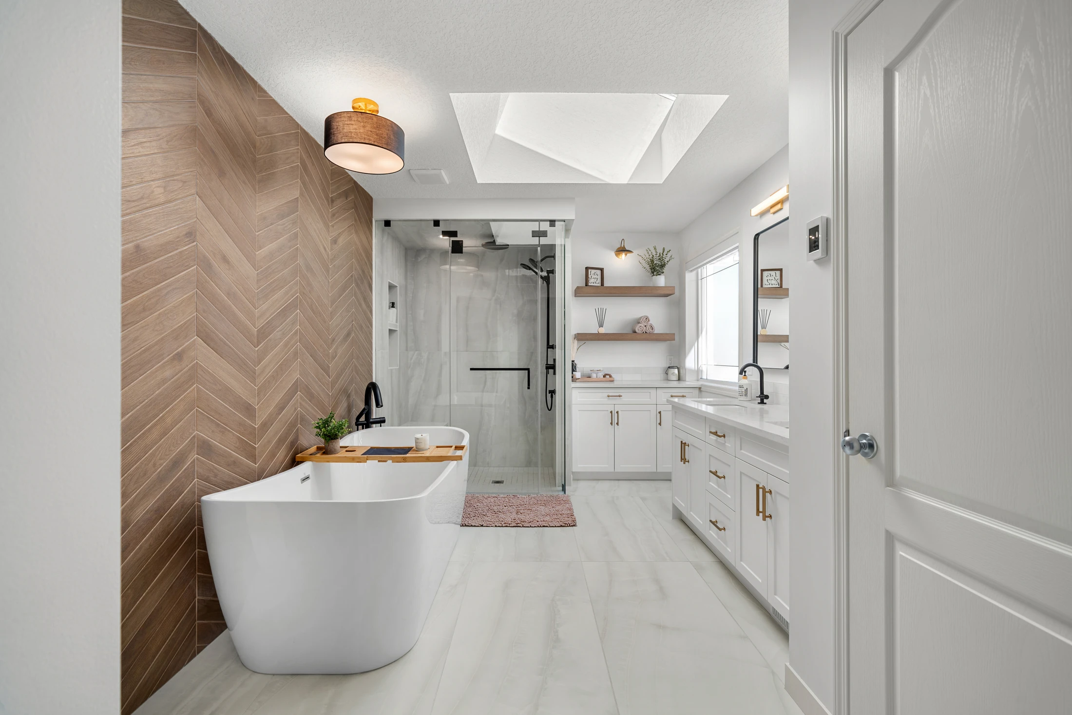 Primary ensuite with a chevron wood accent wall, freestanding tub, and glass shower