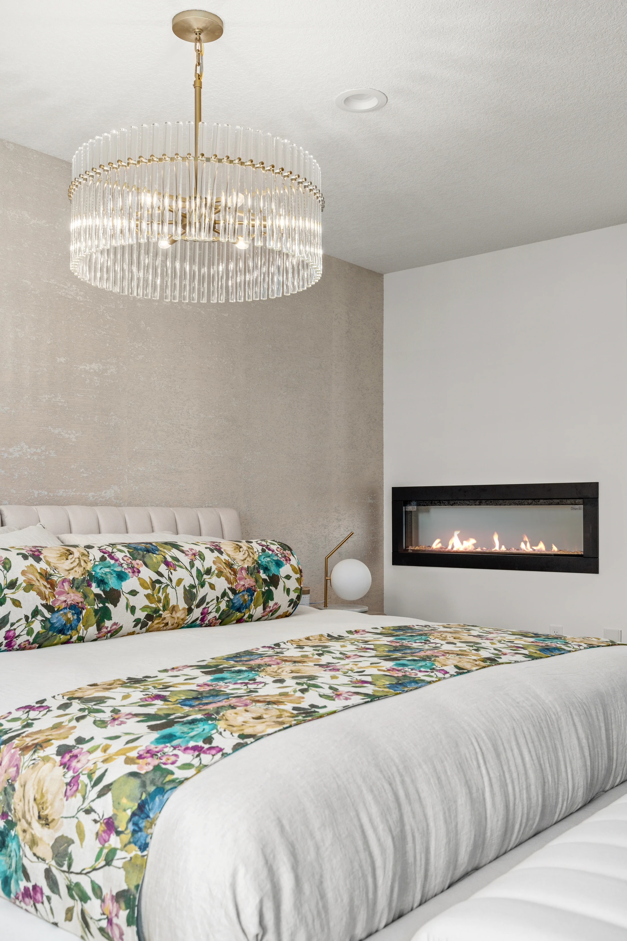 Primary bedroom with a crystal chandelier, gas fireplace, and floral bedding accents